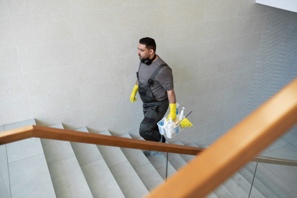 Arbeiter einer Reinigungsfirma geht eine Stiege hinauf