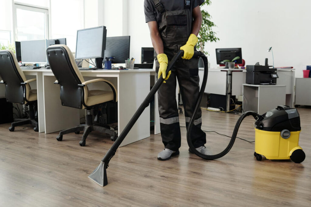 Eine Reinigungskraft saugt ein Büro